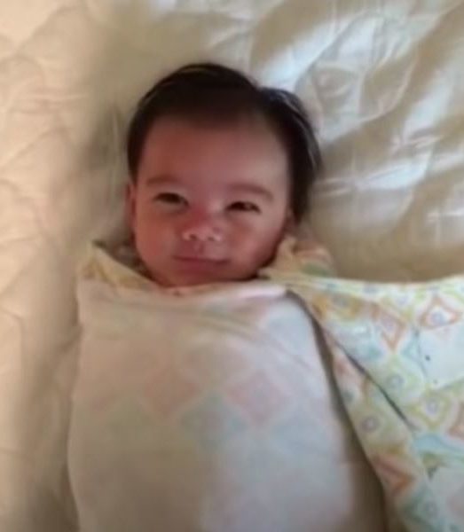 Smiley baby lets arms fly after being unswaddled
